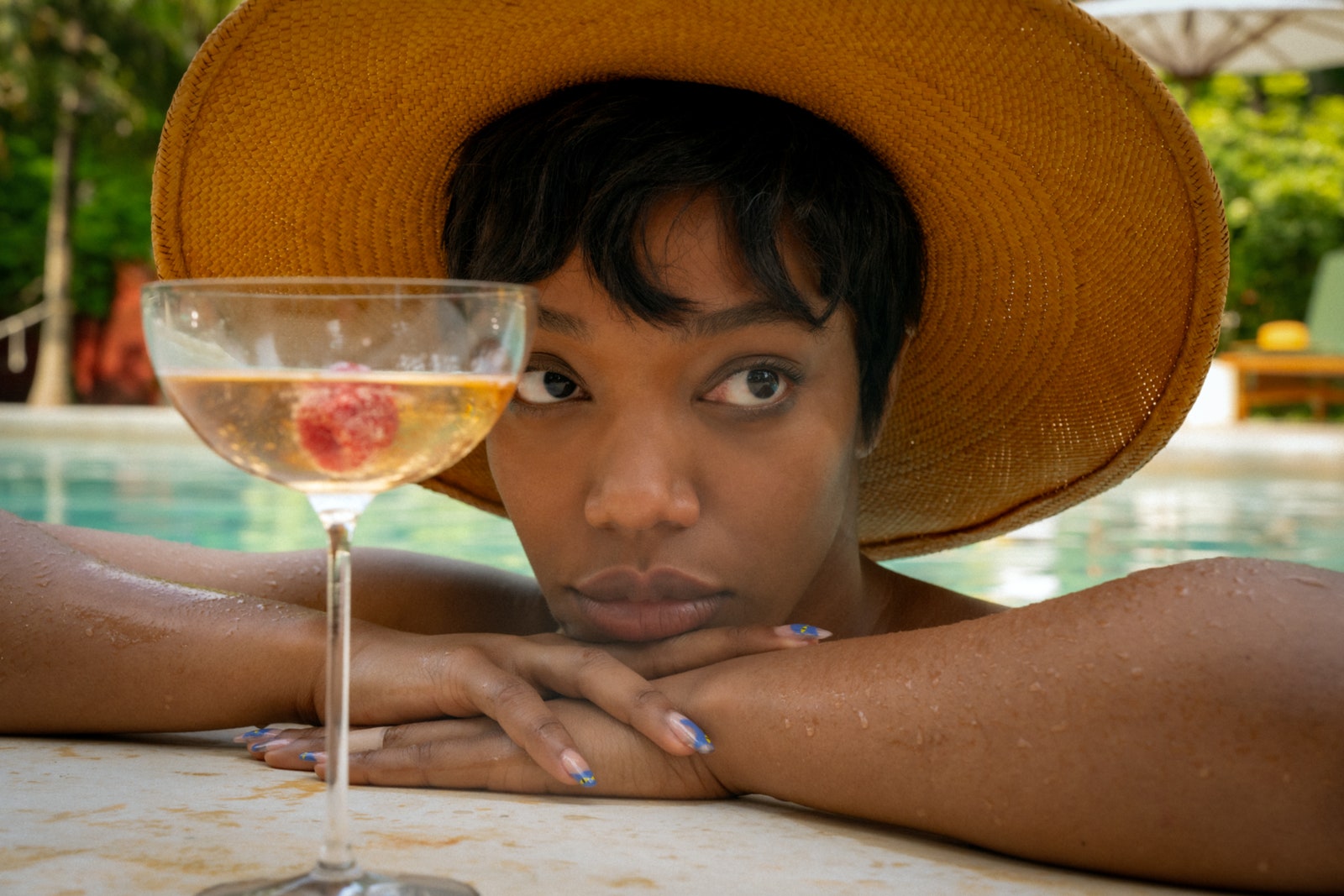 Image may contain Naomi Ackie Clothing Hat Face Head Person Photography Portrait Glass Adult Pool and Water